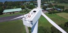 Un homme bronze en haut d'une éolienne. 