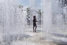 Un enfant se rafraîchit dans des jets d'eau lors d'un épisode de canicule, le 23 juin 2017 à Lyon