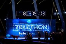 Des invités marchent devant le compteur de dons de l'édition 2016 du Téléthon, à Paris, le 4 décembr