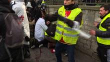 Capture réalisée à partir d'une vidéo de l'AFP TV montrant des "street-medics" portant secours à un "gilet jaune" (caché) qui vient d'avoir la main arrachée par une grenade lancée par des gendarmes lo