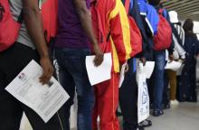 Asylum seekers who have been rescued by the Aquarius rescue ship and another ship in the Mediterranean sea, hold an official document delivered by the French embassy in Malta, as they queue upon their