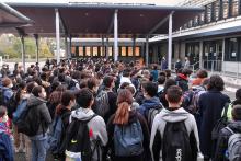 Un homme se recueille devant le collège du Bois d'Aulne à Conflans-Sainte-Honorine, où enseignait Samuel Paty, le 19 octobre 2020