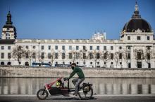 Un homme transporte ses enfants dans la benne avant de son vélo-cargo, le 23 mars 2022 à Lyon